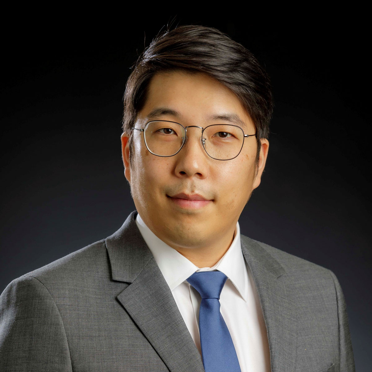 Hunjoo-Lee.jpg Headshot of man with black hair in gray suit in front of black background