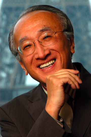 tanaka Headshot of asian man wearing suit in front of blue background
